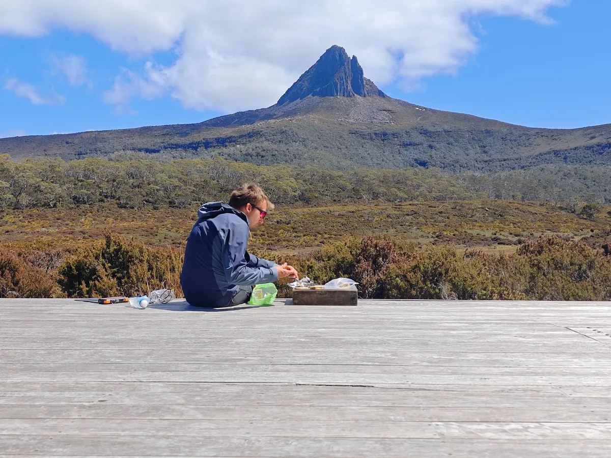 Terrasse en bois, un homme qui mange, montagne en arrière-plan