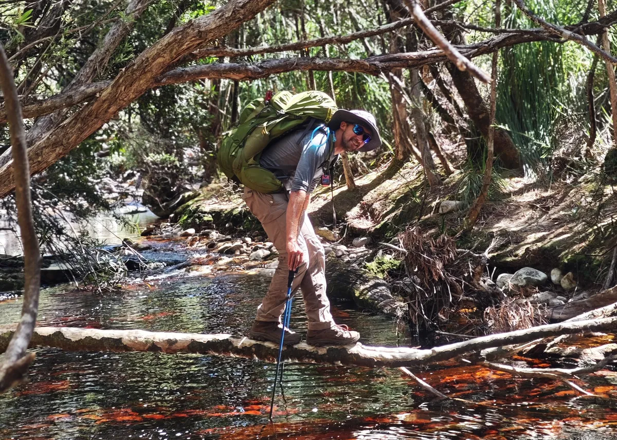 Personne traversant un cours d'eau sur une branche