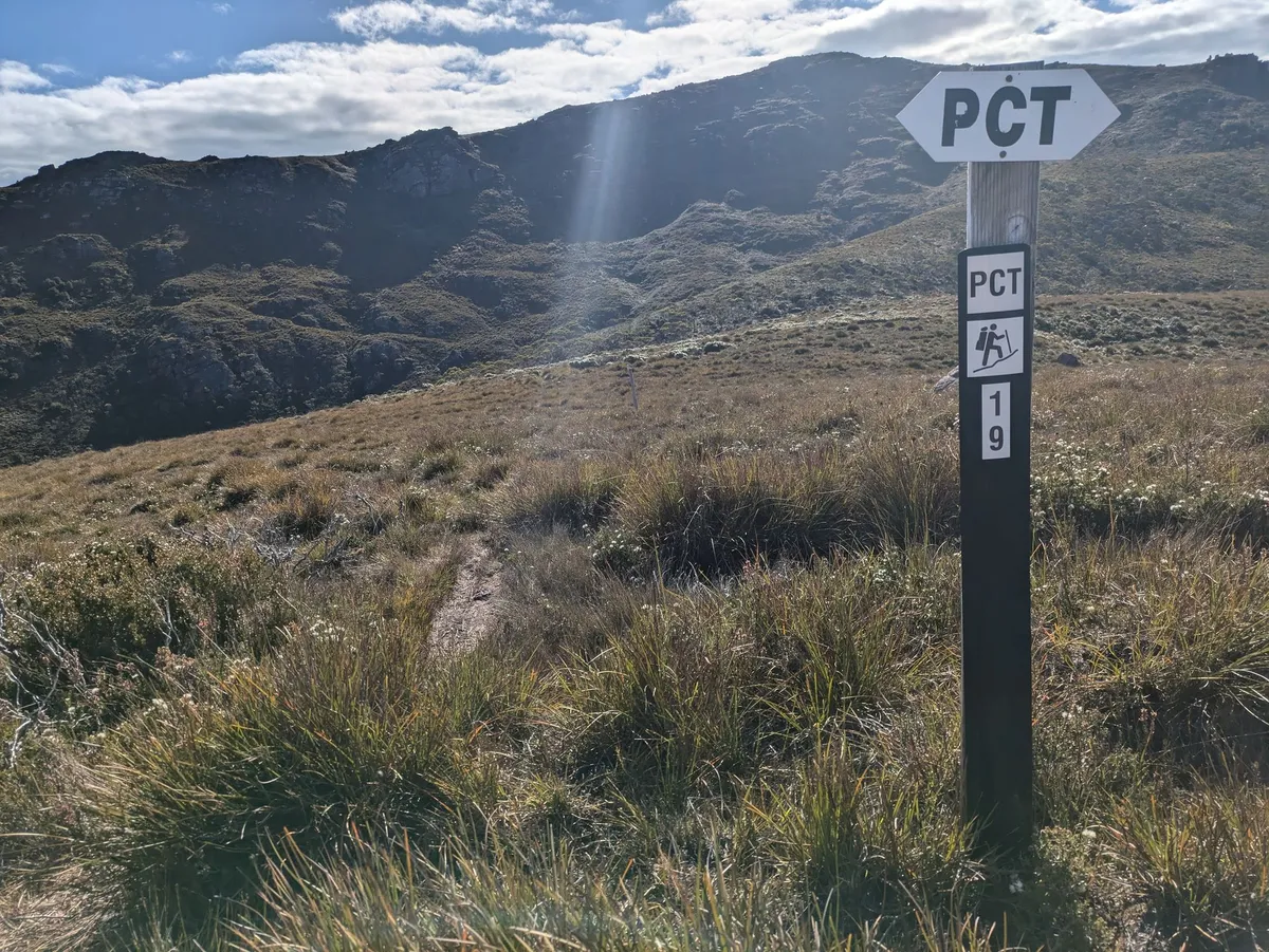 Panneau indiquant PCT et sente partant dans la montagne