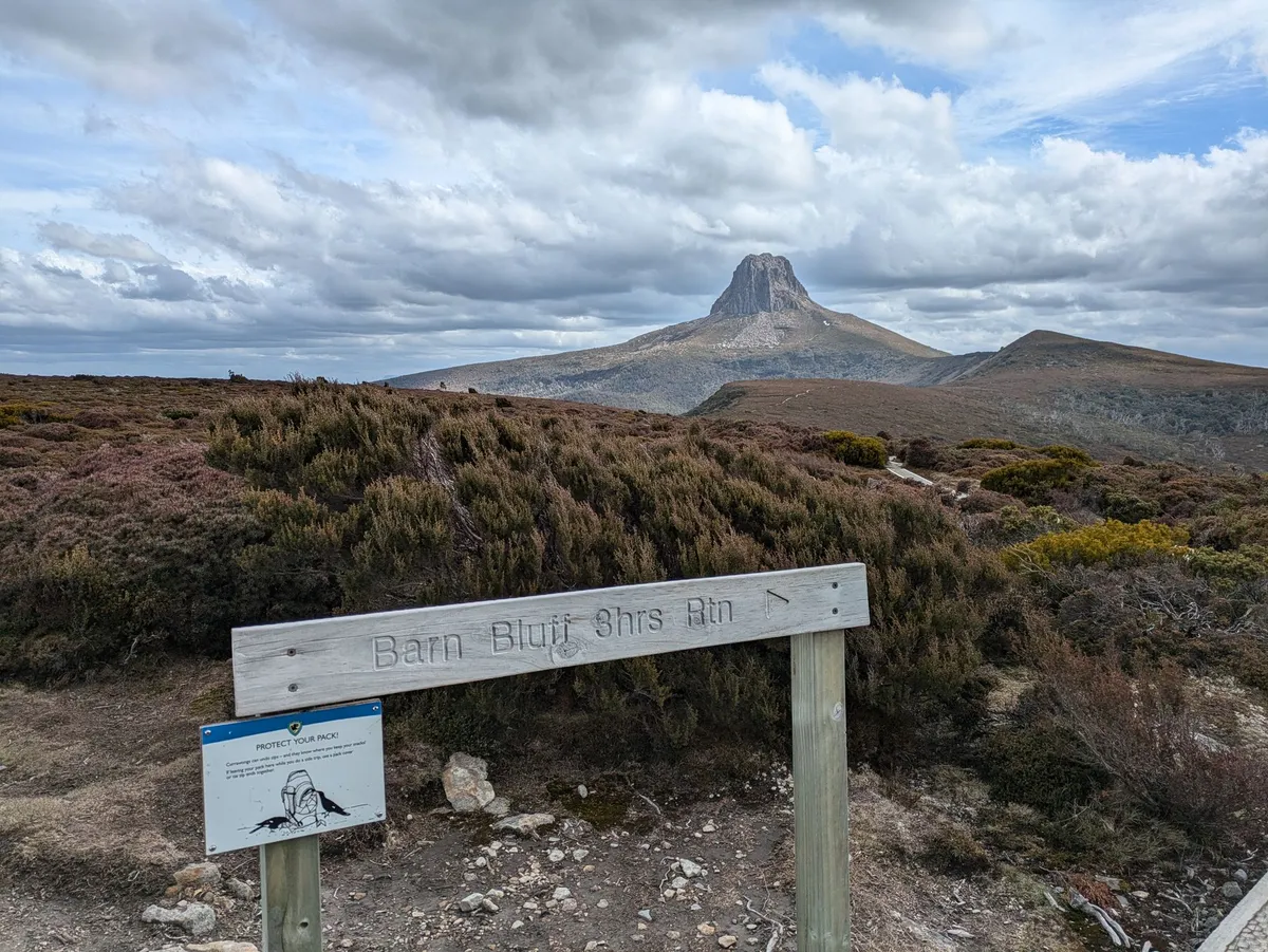 Panneau de bois indiquant Barn Bluff avec le sommet en arrière plan